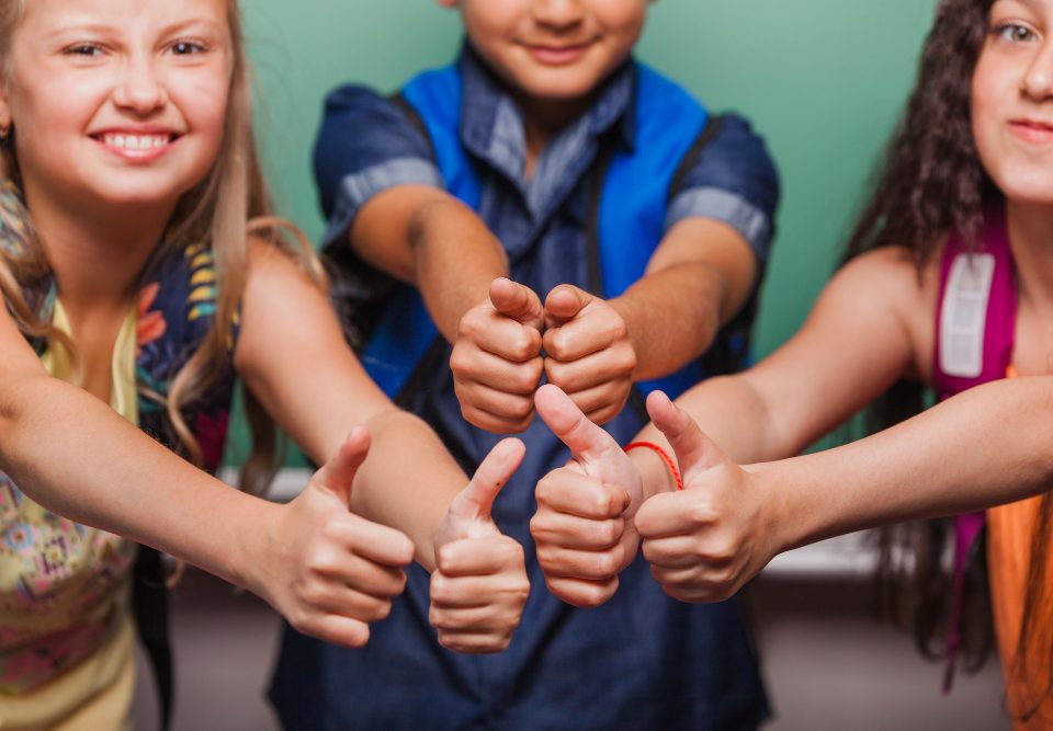 Troje dzieci pokazuje wyciągnięte w górę kciuki