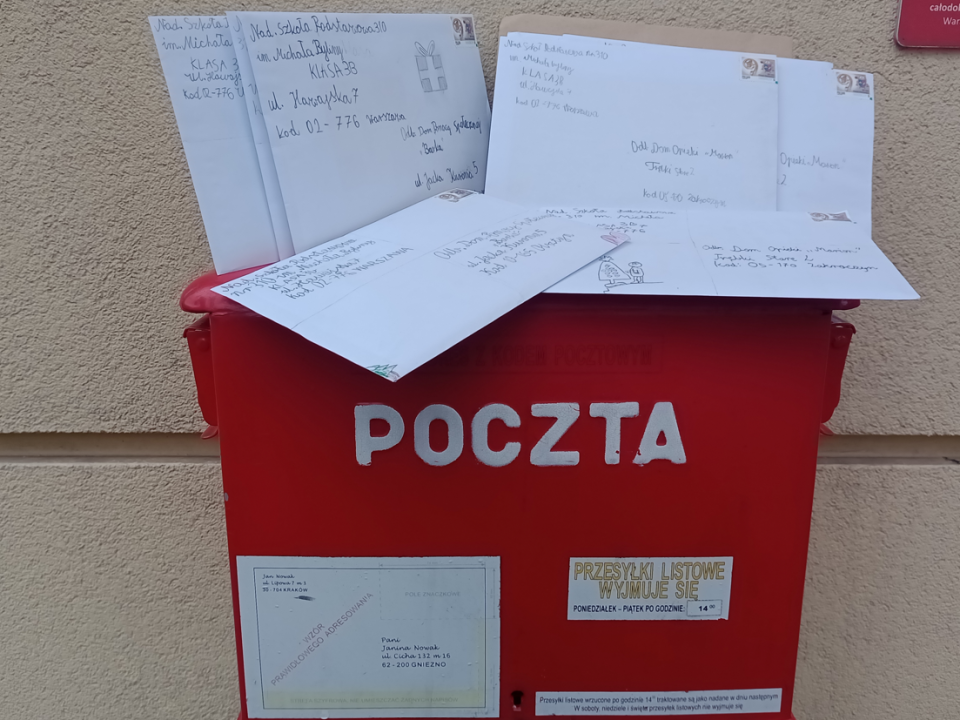 Skrzynka pocztowa na której lezą koperty z kartkami.