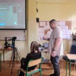 Nauczyciel prowadzi lekcję informatyki, pokazując obraz na projektorze