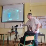 Nauczyciel prowadzi lekcję informatyki, pokazując obraz na projektorze