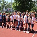 Grupa uczniów w strojach sportowych bierze udział w rozgrywkach sportowych na boisku