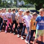 Grupa uczniów w strojach sportowych bierze udział w rozgrywkach sportowych na boisku