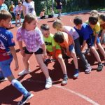 Grupa uczniów w strojach sportowych bierze udział w rozgrywkach sportowych na boisku