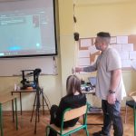 Nauczyciel prowadzi lekcję informatyki, pokazując obraz na projektorze