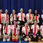 Uczniowie przebrani w stroje sportowe biorą udział w zawodach siatkówki w hali sportowej