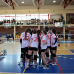 Uczniowie przebrani w stroje sportowe biorą udział w zawodach siatkówki w hali sportowej