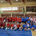 Uczniowie przebrani w stroje sportowe biorą udział w zawodach siatkówki w hali sportowej