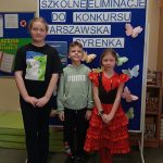 Grupa dzieci na tle niebieskiej tablicy z napisem „szkolne eliminacje do Konkursu Warszawska Syrenka.