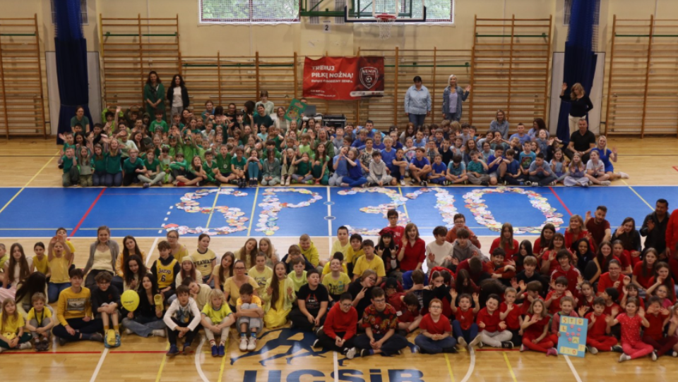 Wszyscy uczniowie ubrani w 4 kolory w hali sportowej wokół logo sp310